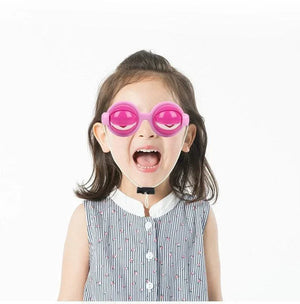 Child wearing pink eye-shaped funny glasses prank toy on white background
