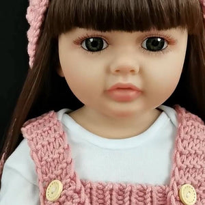 Real-Feel Baby Doll with lifelike silicone skin, brunette hair, and pink knitted outfit