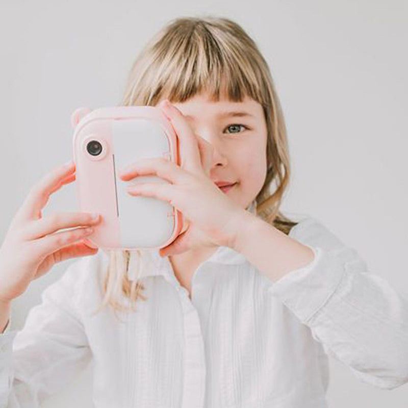 Child holding and using a pink kid-friendly instant print camera for photography fun