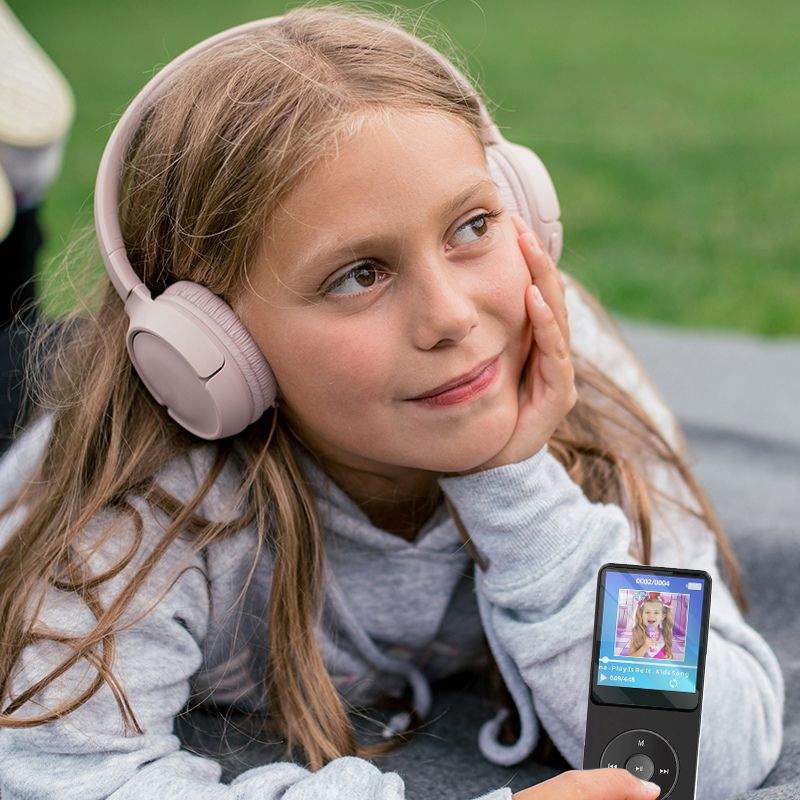 Child listening to MP3 Player With Headset outdoors, enjoying music with comfortable headphones