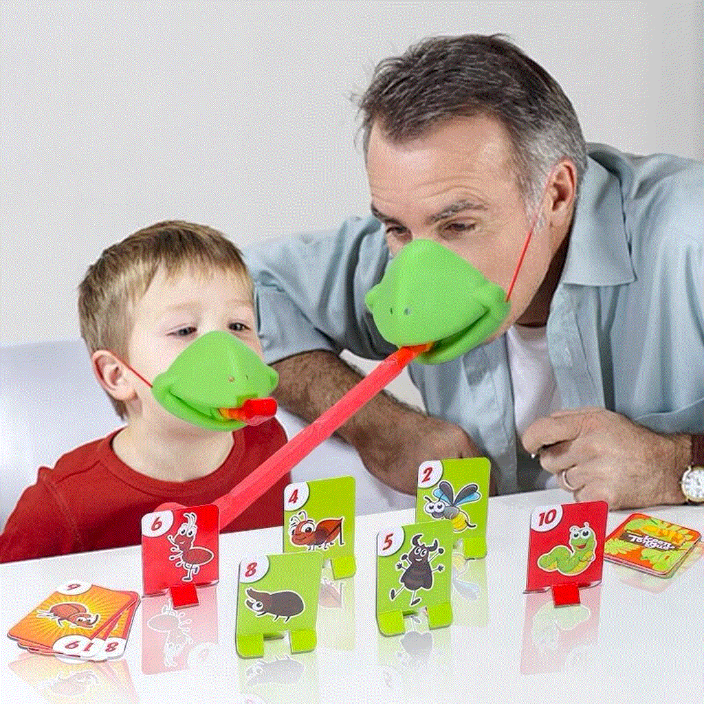 Father and son playing Frog Mouth Tongue-Out table game with green frog masks and red stretchy tongues at home.