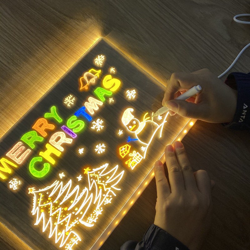 Erasable luminous acrylic message board glowing with colorful Christmas drawing and text on wooden surface