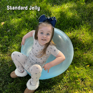 Child playing outdoors sitting on a transparent Giant Jelly Balloon Ball on grass